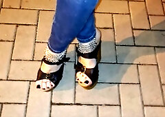 Seductive crossdresser with stunning feet struts on the streets in high heels and tight jeans, tempting boys