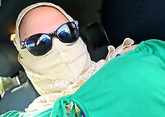 Woman in green and hijab meets stranger by silver SUV in parking lot