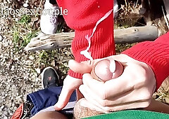 Pretty chick in red is rubbing her boyfriend's dick in the nature, to make him cum