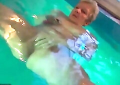 Aged woman is masturbating in the swimming pool, not knowing about a hidden camera across her