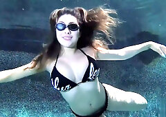 Serena floats submerged in a pool, nude with sunglasses and a tattoo