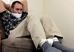 Unable to escape, Brazilian man is restrained in uncomfortable positions with an apple in his mouth during gay bondage session.