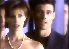 Joan Severance making out with a chap as they move towards a couch, where this babe sits as the dude removes her brassiere to disclose her boobs. From